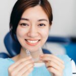Asian woman holding clear aligners in a dental clinic