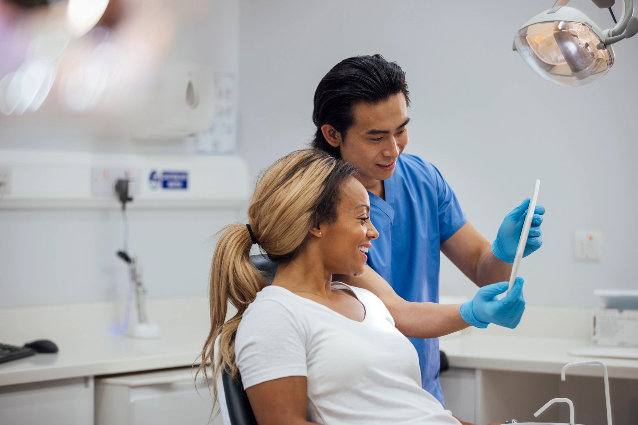 Asian dentist showing a patient her smile after treatment
