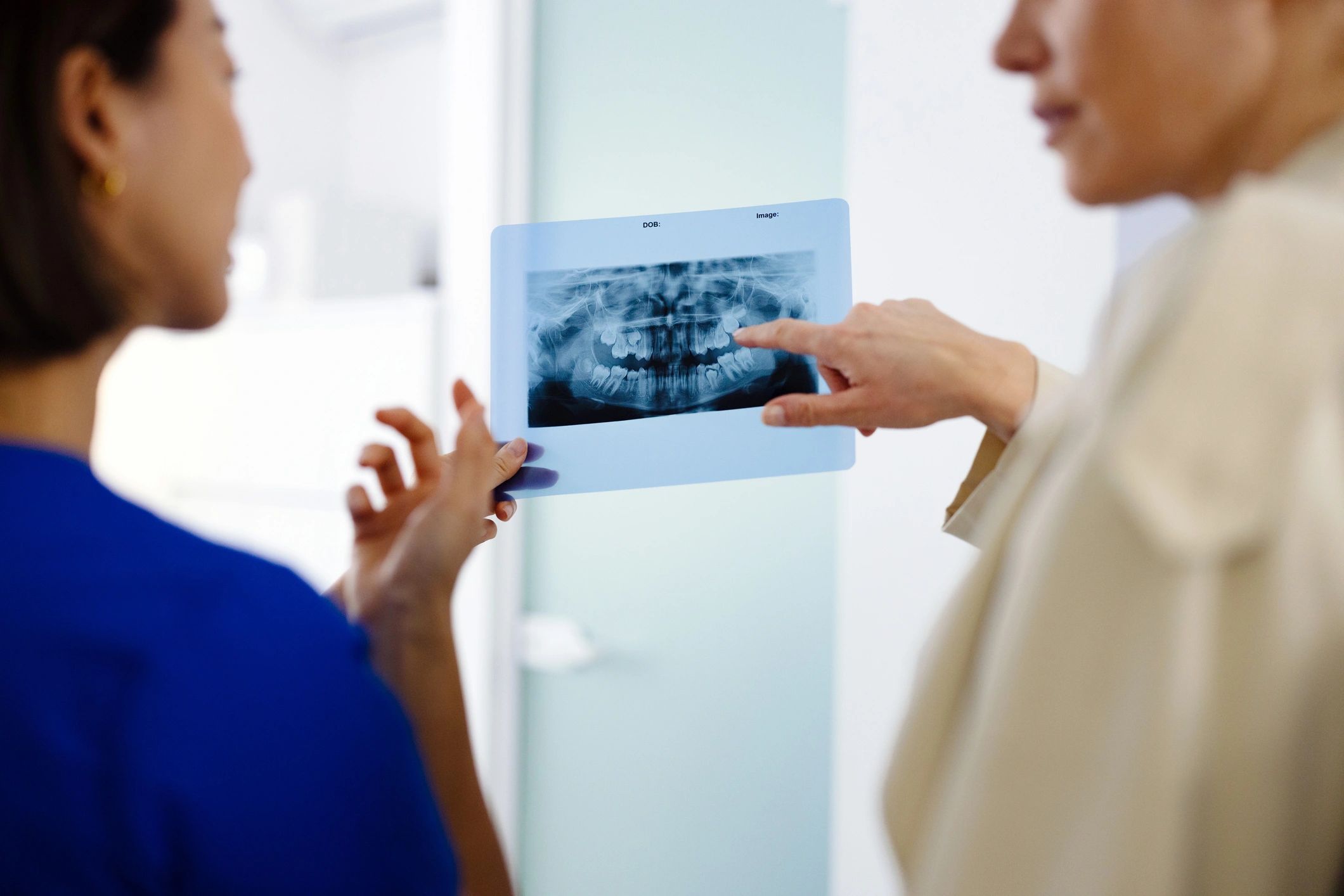 Asian dentist reviewing a dental x-ray with a patient in a modern clinic